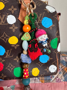 The bag charm with the red rose and the funny little baseball guy