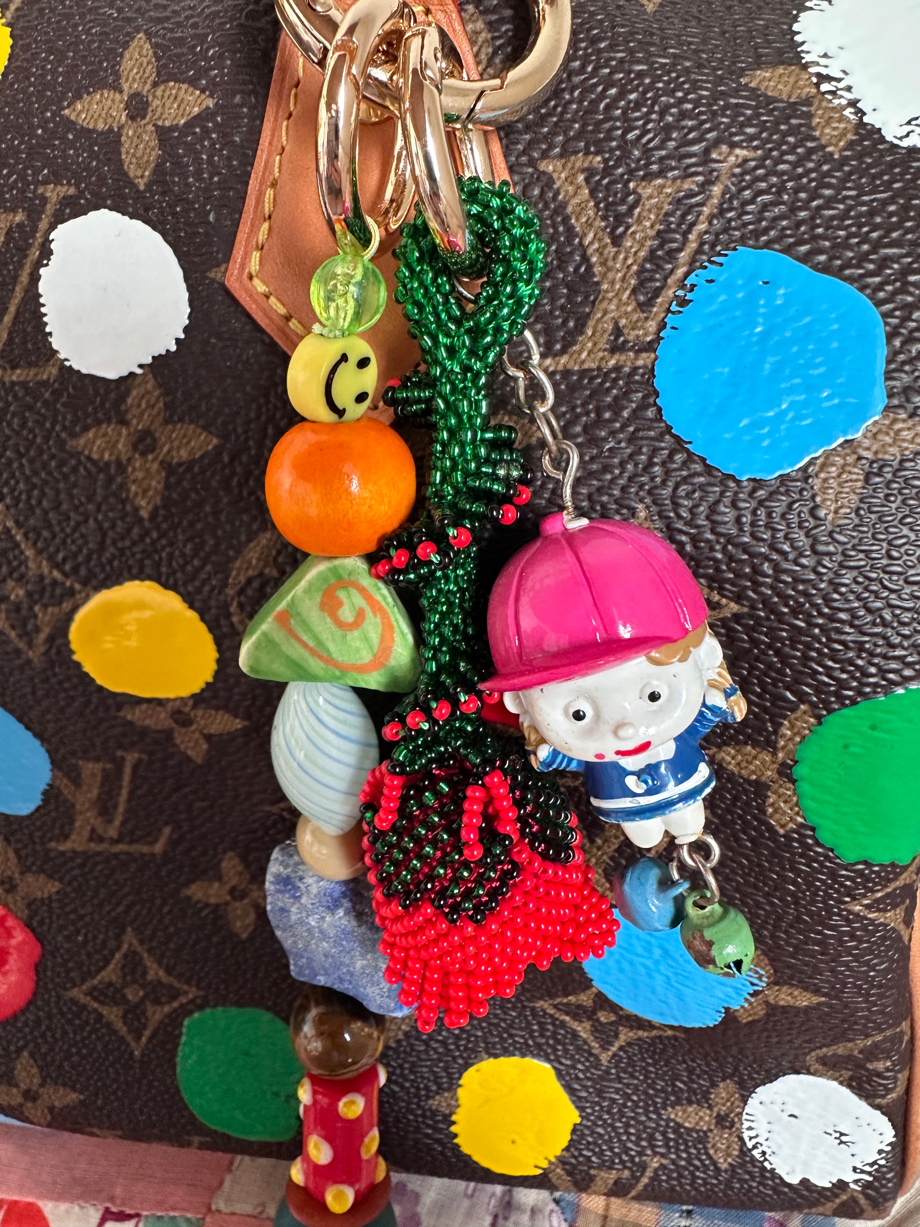 The bag charm with the red rose and the funny little baseball guy