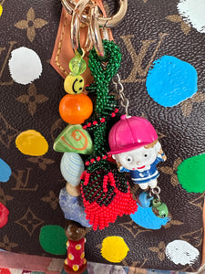 The bag charm with the red rose and the funny little baseball guy