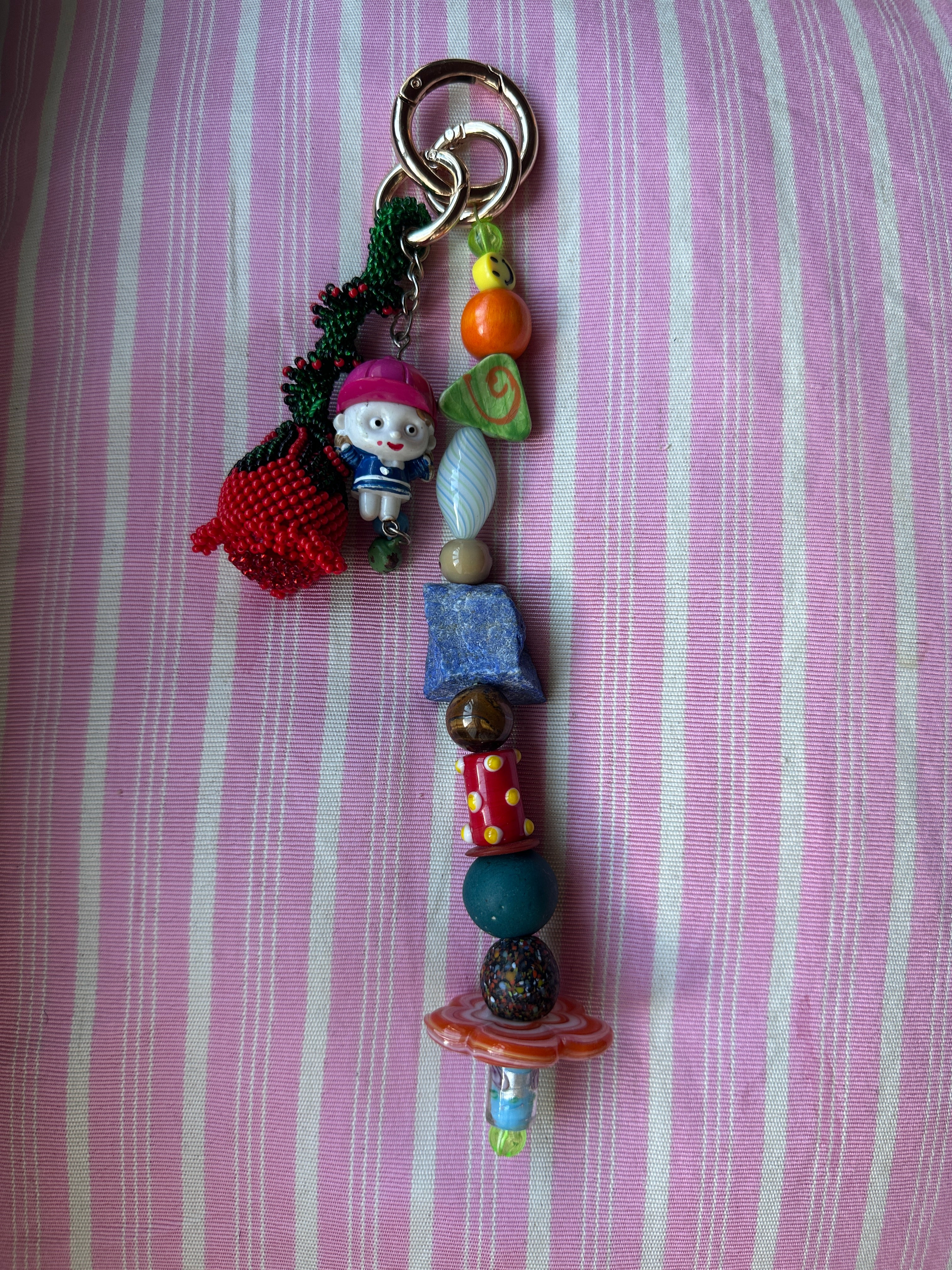 The bag charm with the red rose and the funny little baseball guy