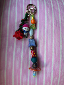 The bag charm with the red rose and the funny little baseball guy